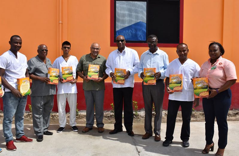Minister of State, Mr. Joseph Harmon; Director of the Institute of Applied Science and Technology (IAST), Professor Suresh Narine and Regional Executive Officer of Pomeroon-Supenaam (Region Two), Mr. Rupert Hopkinson and staff of the Morning Glory Rice Cereal Plant, pose with the boxes of their cereal