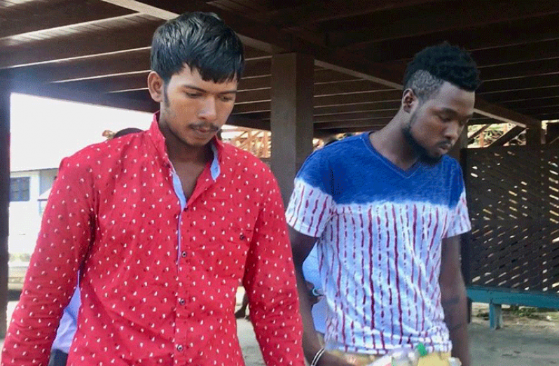Anonth Boodrage (in red) and Ricardo Fraser were on Friday charged with the murder of four fishermen