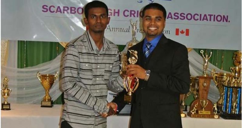 HACC skipper Hemnarine Chattergoon (left) collects the championship trophy from SCA registrar/statistician Shiv Persaud