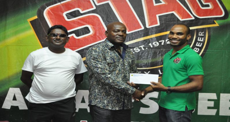 STAG Brand Coordinator Lindon Henry presents the sponsorship cheque to EBFA president Franklin Wilson.