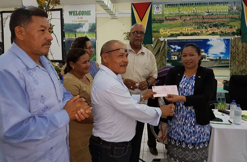 Minister within the Ministry of Communities, Dawn Hastings-Williams handing over the cheque
to a representative of the Paramakatoi Village Council for a water supply improvement project