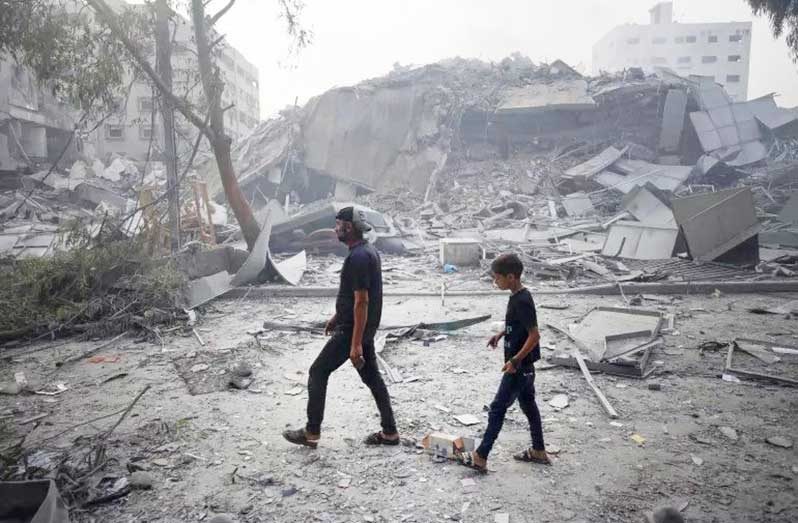 A child and his father as they pass through the rubble of buildings in Gaza (UNICEF/UNI448939/Eyad El Baba)