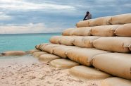 A man fishes sitting on sandbags which protect the Pacific Ocean island nation Tuvalu against sea erosion (UNICEF/Lasse Bak Mejlvang)