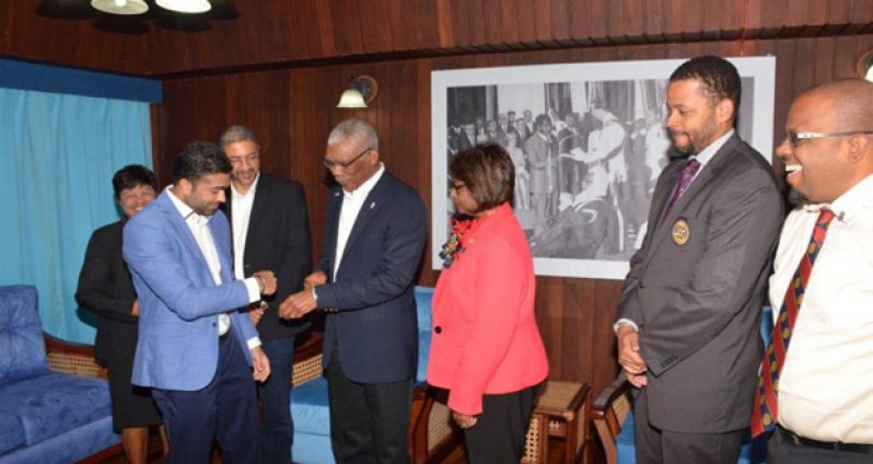 President David Granger and Rotary Club of Georgetown Secretary Ralph Persaud compare cricket bands, while the other members of the Club look on