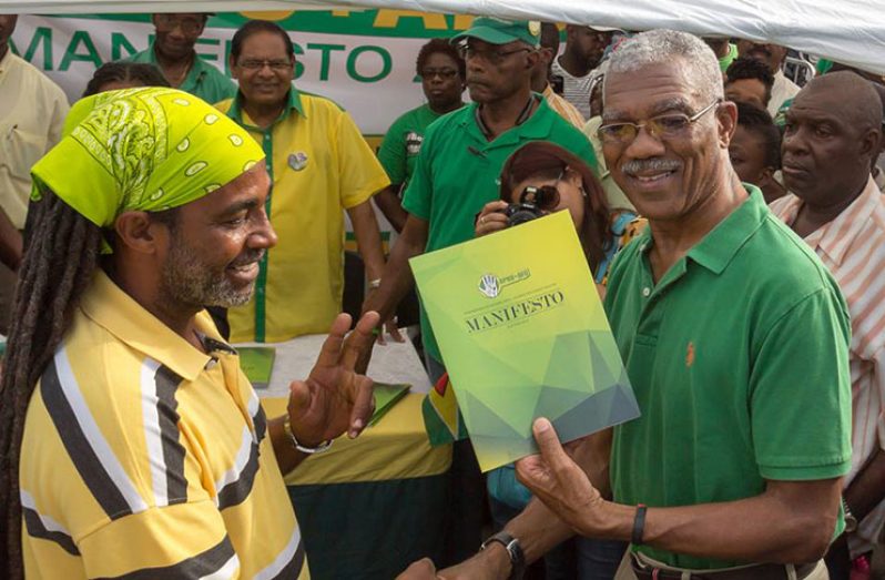 Flashback! President David Granger (then candidate Granger) presents a copy of the APNU+AFC manifesto to a citizen during the 2015 elections campaign. Also in photo is Prime Minister Moses Nagamootoo