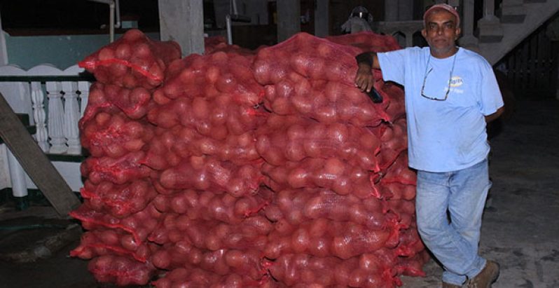 Nadir Mustakeen stands next to a pile of coconut which will be shipped off of Wakenaam