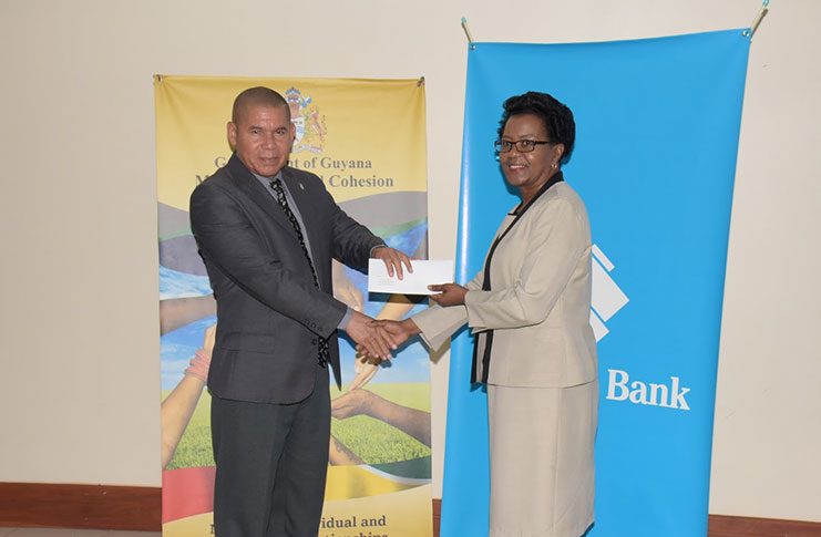 Minister of Social Cohesion, Dr. George Norton receives the cheque from General Manager Operations,  Republic Bank Guyana Limited, Ms. Denise Hobbs