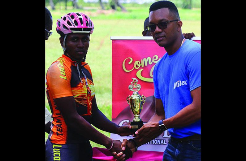 Team Alanis’ Kemuel Moses (left) accepts his winner’s trophy and prize money from a representative of DeSinco Trading at the National Park on Saturday.