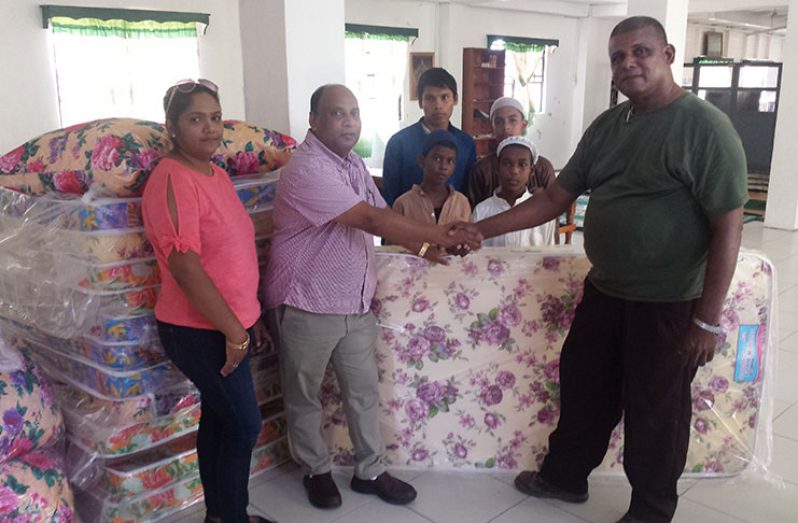 Mr. Dennis Charran, Managing Director, Comfort Sleep, and his wife,  Sabita Charran, present mattresses and pillows to the Saheed Orphanage Caregiver, Michael Akbar.  Looking on are boys from the Orphanage.