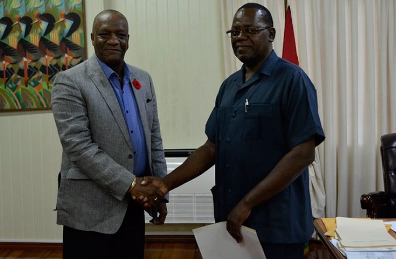 Minister of State, Mr. Joseph Harmon, shakes hands with the Commissioner of the newly established Board of Inquiry, Mr. Winston Cosbert, who has been tasked with probing  allegations of malpractices in the procurement division of the Ministry of Public Health
