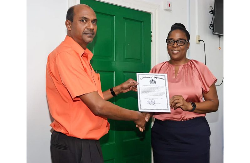 Chief Co-operatives Development Officer - Ministry of Labour, Janaknauth Panchu (left), with member of the newly registered credit union (MoL photo)