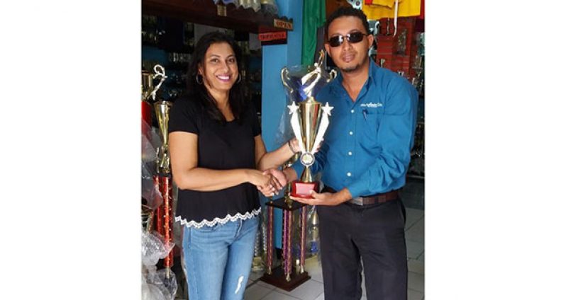 Mrs. Devi Sunich of Trophy Stall hands over one of the trophies to National Player / Caribbean Champ Luis Ramirez-Merlano