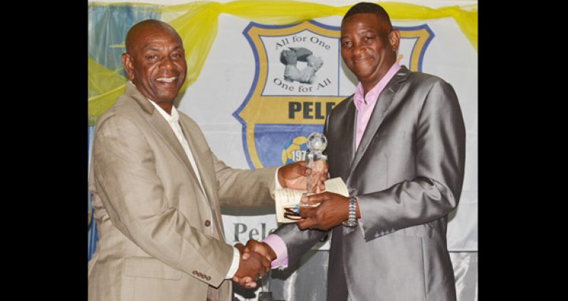 Inductee into the Pele FC Hall of Fame, Dennis `Chow’ Hunte (left), accepts his award from former national player Linden Carter.