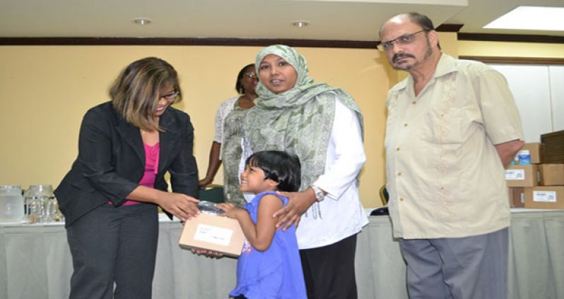 A member of the Presidential Non-Communicable Disease (NCD) Commission handing over a diabetes testing kit to one of the beneficiaries as Minister of Health, Dr Bheri Ramsaran looks on