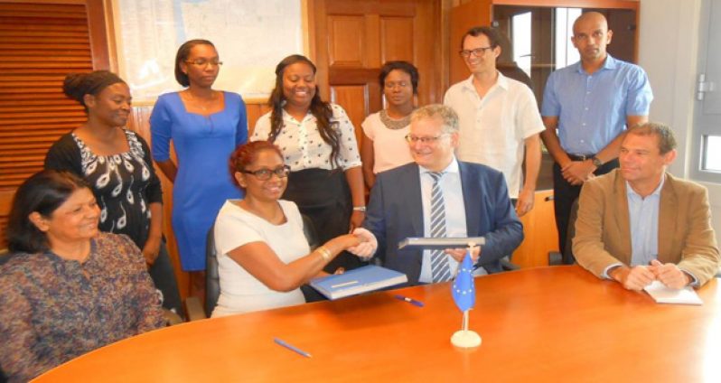 Ambassador Videtic and Ms Madray exchange copies of the contract in the presence of EU Delegation and ChildlinK Inc officials