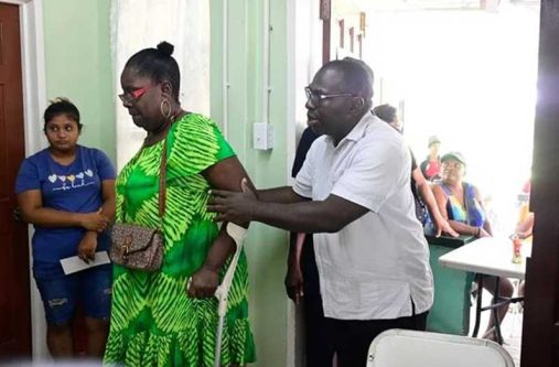 Minister within the Office of the Prime Minister with responsibility for Public Affairs, Kwame McCoy, assists staff at the Mocha Community Centre during the distribution exercise