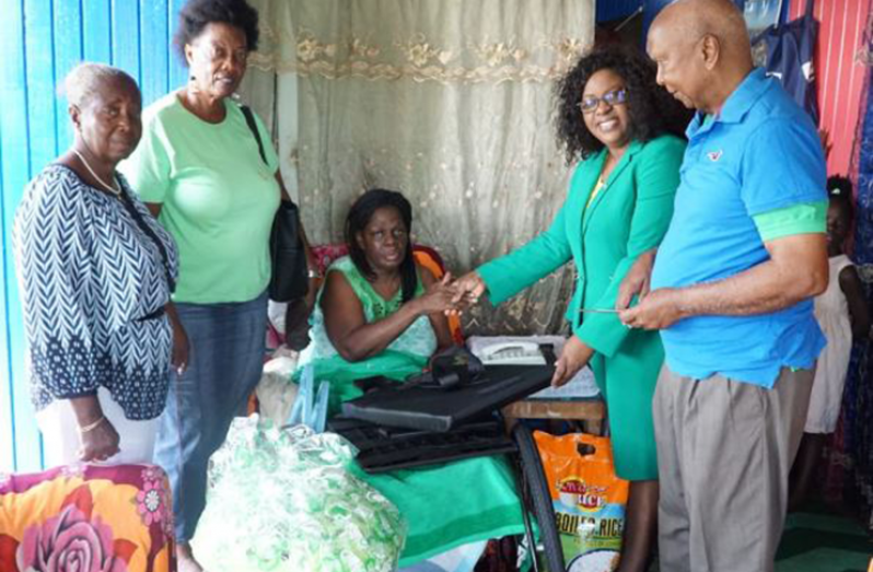 Jenifer Hutson received the wheelchair from Minister within the Public Health Ministry, Dr. Karen Cummings, as others look on.