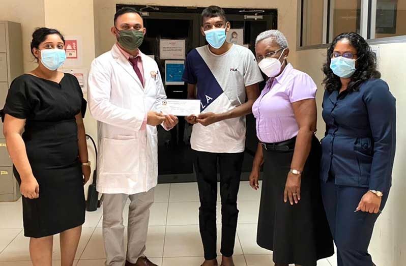 Christopher Sukhu (centre) receives a donation from a representative of the Humanitarian Mission-Guyana Inc., Dr. Shailendra Sugrim, while in the company of other representatives