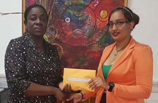 Minister within the Ministry of Education, Nicolette Henry, hands over the envelope of cash to Safiya Gafoor of the IAC