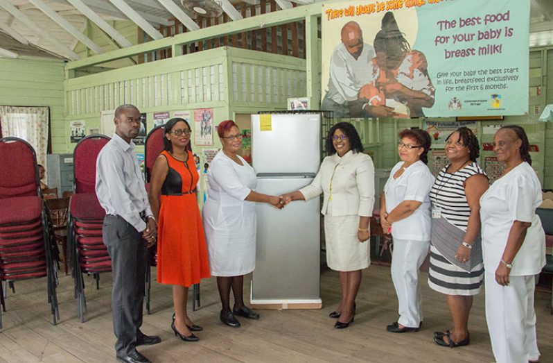 Minister within the Ministry of Public Health, Dr. Karen Cummings, handing over the refrigerator and chairs to Nurse Marilyn Gordon in the presence of officials of the City Council and nursing staff of the centre