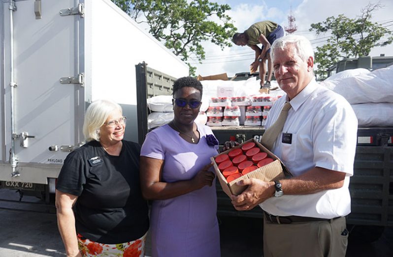 Elder William T. Bohne handing some food items to CDC’s Odetta Giddings. At left is his wife, Elder Sandra F. Bohne )Photos by Carl Croker)