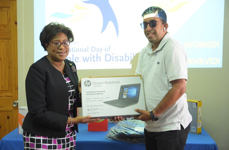 Public Telecommunications Minister, Cathy Hughes presenting one of the laptops to GCOPD representative Ganesh Singh