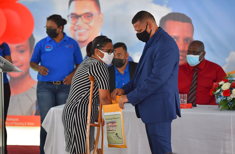 Woman Police Khuslucinda Doobay pulled her lot number from a bag held by Minister of Housing and Water Collin Croal at the title/transport distribution done in Anna Regina under the theme “Dream Realised 2021”