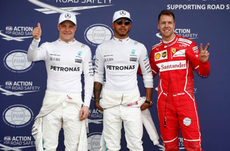 Mercedes driver Lewis Hamilton (C) of Britain reacts after setting pole position in qualifying alongside team mate Valtteri Bottas (L) of Finland and Ferrari's Sebastian Vettel of Germany. REUTERS/Brandon Malone