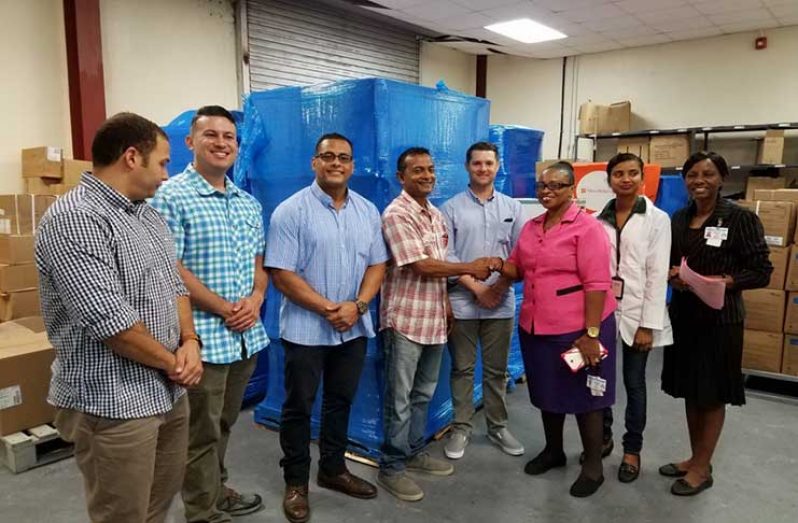 In picture, Sharir Chan, GMRs COO, in pink plaid shirt hands over to staff of the Materials Management Unit (MMU) of the  MOPH a previous shipment of medicines destined for Suddie Hospital. Also in picture are members of the Humanitarian Assistance Program of the U.S. Embassy, Georgetown