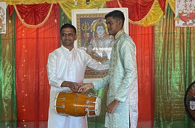 The businessman (left) hands over a drum to a representative of a mandir in Region Two