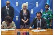 GECOM Chairwoman, Justice [ret’d] Claudette Singh and UNDP Resident Representative Berdi Berdiyey sign the electoral support agreement while British High Commissioner, H.E. Jane Miller and other officials look on