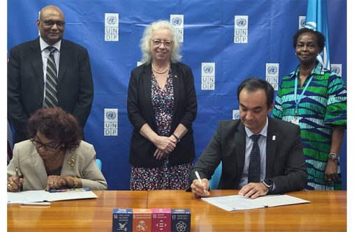 GECOM Chairwoman, Justice [ret’d] Claudette Singh and UNDP Resident Representative Berdi Berdiyey sign the electoral support agreement while British High Commissioner, H.E. Jane Miller and other officials look on