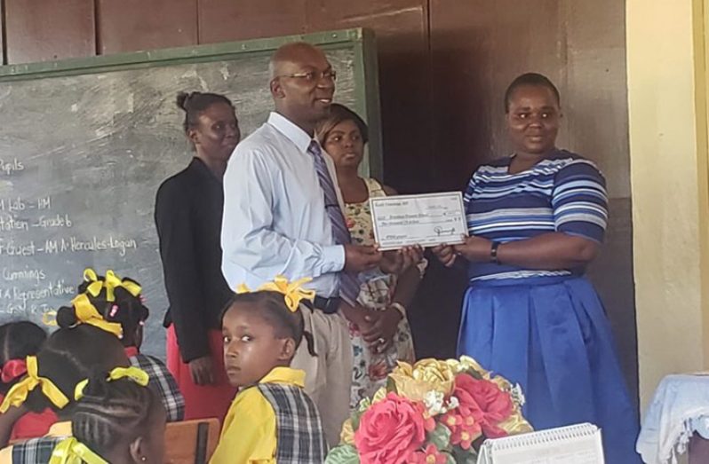 Dr. Keith Cummings hands over the cheque to a teacher of the school
