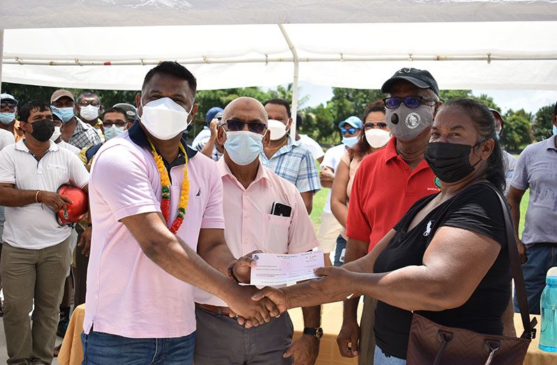 Minister within the Ministry of Public Works, Deodat Indar hands over a flood-relief grant to Wakenaam farmer, Rajpatty Dhanaat (Elvin Croker photo)