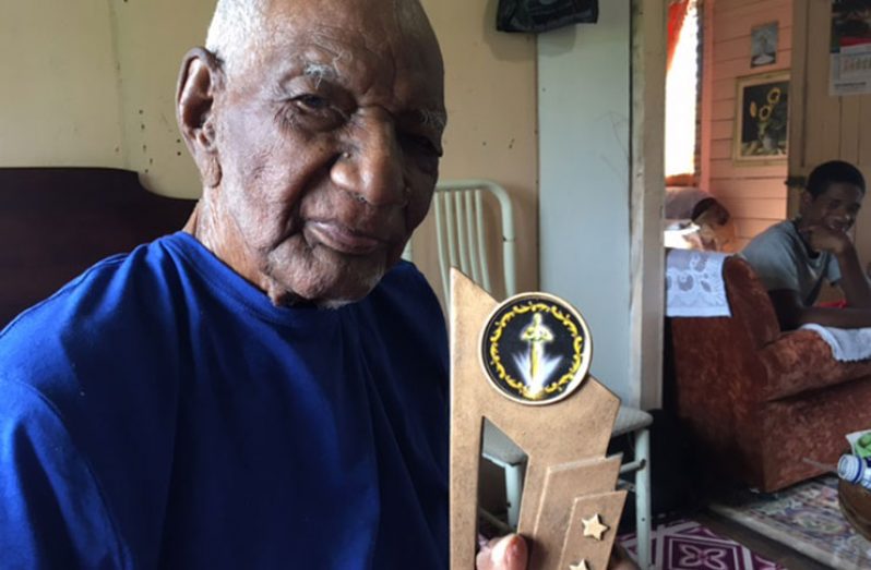 Likely the oldest Father in Guyana, a recent photograph of 106 year old Gladstone Mack aka Uncle Mackie, at his South Sophia home holding one of his many trophies. (Photo by Francis Quamina Farrier)