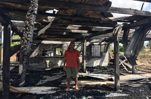 A distraught Baijnauth Baichand is surrounded by ashes after his home was destroyed by fire