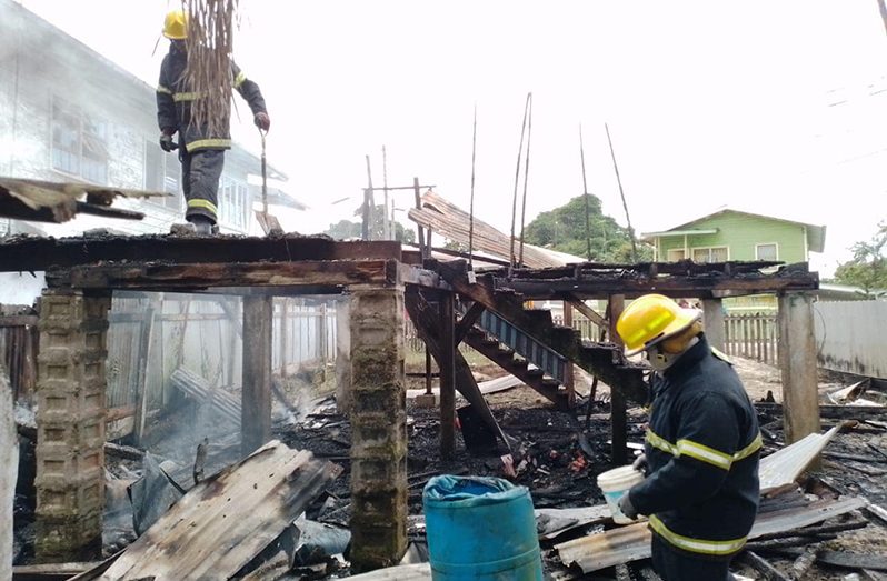 Firefighters examining the aftermath of a fire that has displaced four persons (Guyana Fire Service photo)