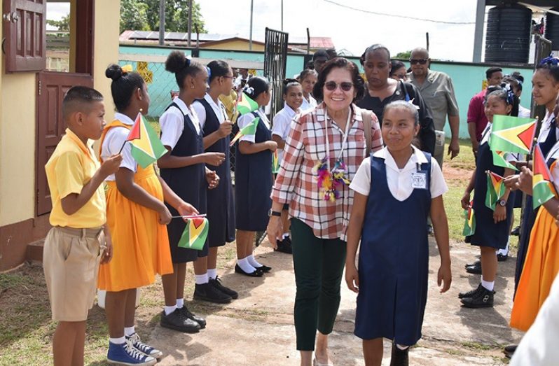 First Lady, Mrs. Sandra Granger, being escorted into the Regional Boardroom, Mahdia, Potaro-Siparuni (Region Eight) by a student of the Mahdia Secondary School. Also pictured are students from the Mahdia Primary and Secondary Schools who greeted Mrs. Granger as she walked by