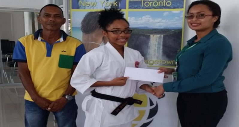 Black belt Aliya Wong (centre) collects her ticket from Fly Jamaica Marketing Representative Youlanda Foster (right) as senior instructor Sensei Jeffrey Wong (left) looks on.