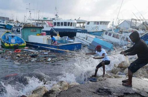 Fishermen pull a boat damaged by Hurricane Beryl back to the dock at the Bridgetown Fisheries in Barbados (Associated Press)