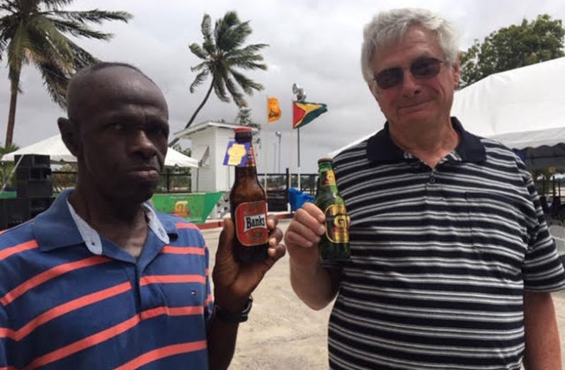 Shareholders Clinton Dash of Onderneeming and Canadian-born Guyanese citizen David Goodreau of Jacklow, Pomeroon, toast BANKS DIH at Airy Hall. The Essequibo River is in the background. (Photo by F.Q. Farrier)