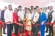 President Dr. Irfaan Ali accompanied by Tourism, Industry and Commerce Minister, Oneidge Walrond, Inter-Development Bank (IDB) country representative, Lorena Soloranao Salazar  and several students cutting the ceremonial ribbon, declaring the US$12M Guyana National Bureau of Standards (GNBS) laboratory and administrative building open. (Office of the President Photos)