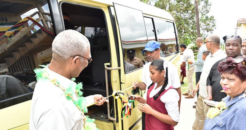 President David Granger and GBTI’s Chief Executive Officer, Mr. John Tracey, assist a student with the ceremonial ribbon-cutting to commission the bus, while Minister of Social Cohesion, Ms. Amna Ally, looks on