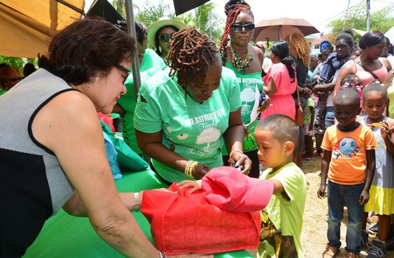 This little boy holds on to his hamper as First Lady, Mrs. Sandra Granger interacts with him (Ministry of the Presidency photo)