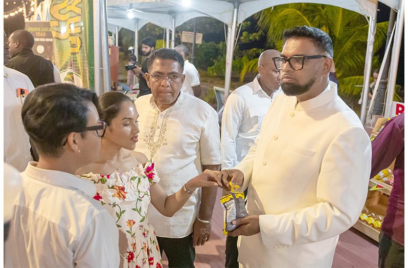 President Dr. Mohamed Irfaan Ali, the First Lady, Mrs. Arya Ali, enjoying a packet
of tasty chips at the farmers’ market. Also pictured are Minister of Tourism and
Culture Susan Rodrigues, and Minister of Agriculture Zulfikar Mustapha. At the
event, which continues today, local farmers and agro-processors are displaying,
selling and having a sampling exercise of fresh and organic products. The event
is part of Agriculture Month activities (Delano Williams photo)