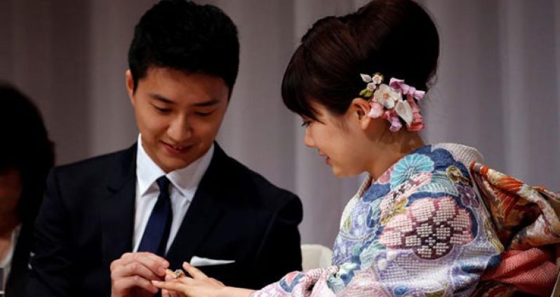 Japan's table tennis Olympian Ai Fukuhara (R) has her wedding ring placed on her finger by her husband Taiwan's table tennis Olympian Chiang Hung-chieh at a news conference to announce their marriage in Tokyo, Japan, yesterday. (REUTERS/Toru Hanai)