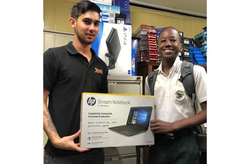 St Rose’s High student, Garfield Dover (right) receiving a laptop from Brandon Henrique, the son of Game Xpress owner, Audie Henrique