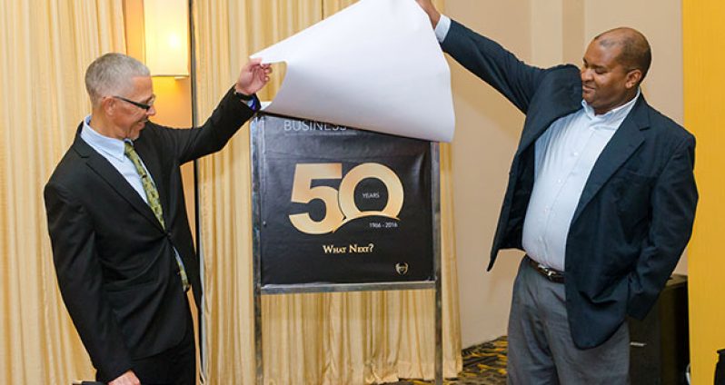 Minister of Business Dominic Gaskin (left) and former GCCI President Lance Hinds unveil the Business Magazine at its launch at the Pegasus Hotel
