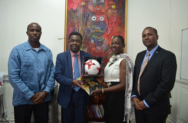 FIFA Director Véron Mosengo-Omba exchange tokens with Hon. Minister Nicolette Henry (centre) in the presence of GFF president Wayne Forde (r) and first vice-president Ret. Brigadier Bruce Lovell (l).