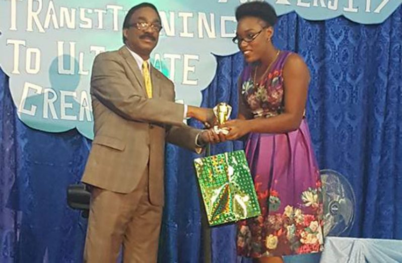 Minister Basil Williams presenting a gift to top CAPE performer Ornissa Gordon